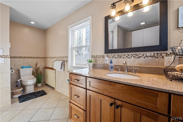 bathroom with tile patterned flooring, vanity, tile walls, and toilet