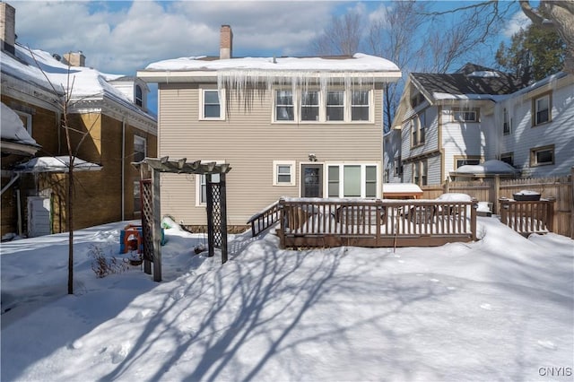 snow covered house featuring a wooden deck and a pergola