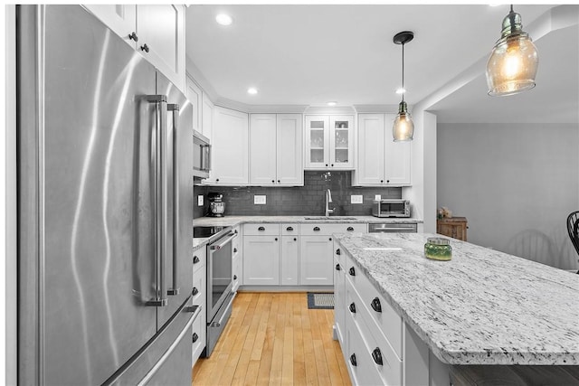 kitchen featuring a kitchen island, decorative light fixtures, white cabinetry, sink, and stainless steel appliances