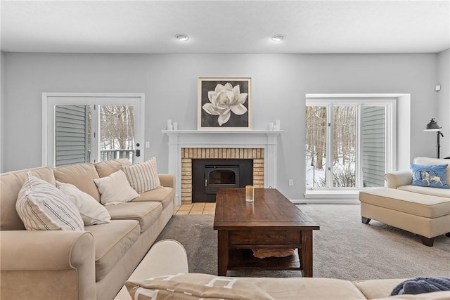 carpeted living room featuring a brick fireplace and a wealth of natural light