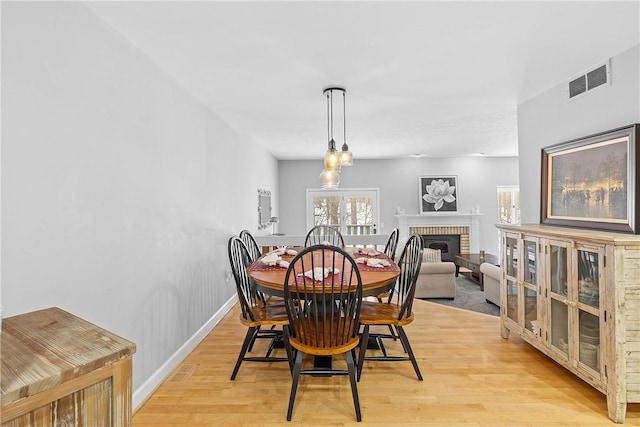 dining room with a fireplace and light wood-type flooring