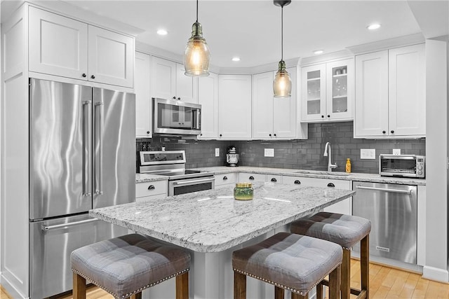 kitchen with sink, appliances with stainless steel finishes, a kitchen breakfast bar, a center island, and white cabinets