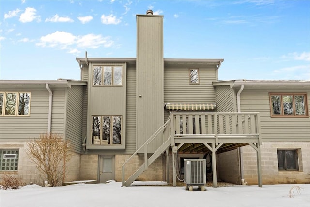 snow covered house featuring central AC unit