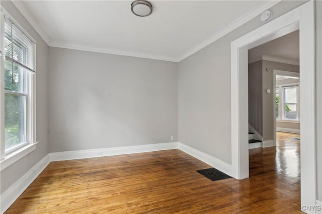 empty room with hardwood / wood-style flooring and ornamental molding