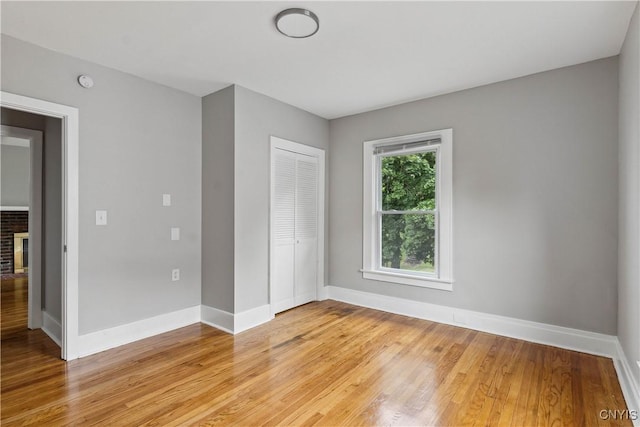 unfurnished bedroom featuring a closet, a brick fireplace, and light hardwood / wood-style flooring