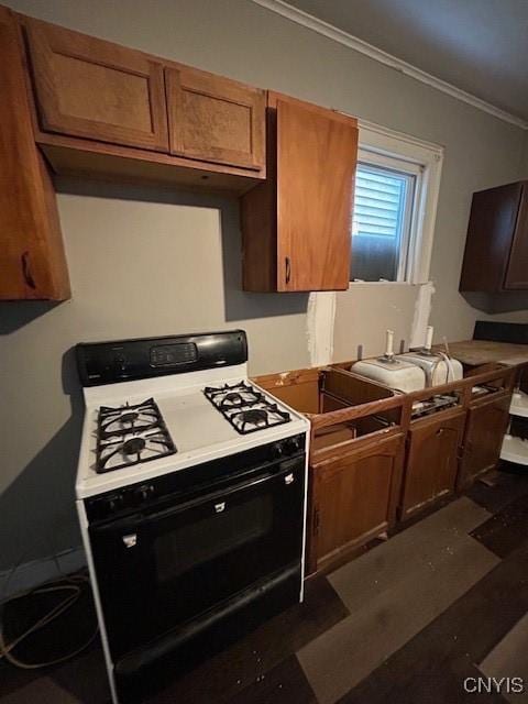 kitchen with dark wood-type flooring, ornamental molding, and range with gas cooktop