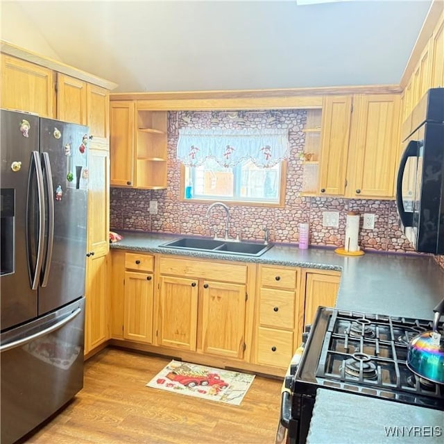 kitchen featuring light hardwood / wood-style floors, gas stove, backsplash, stainless steel fridge, and sink