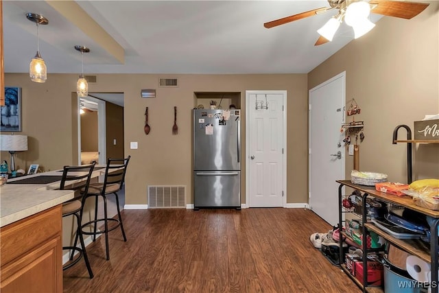 kitchen featuring dark wood-type flooring, light countertops, visible vents, and freestanding refrigerator