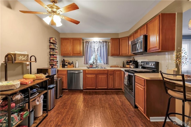 kitchen with dark wood finished floors, a sink, light countertops, appliances with stainless steel finishes, and tasteful backsplash