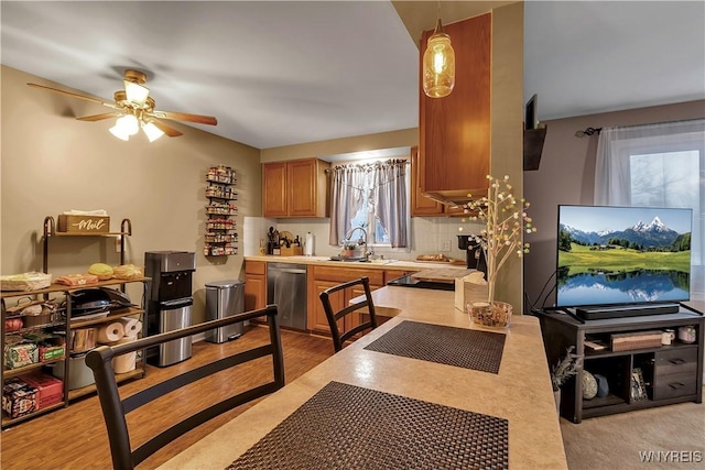 kitchen with backsplash, ceiling fan, light countertops, stainless steel dishwasher, and a sink