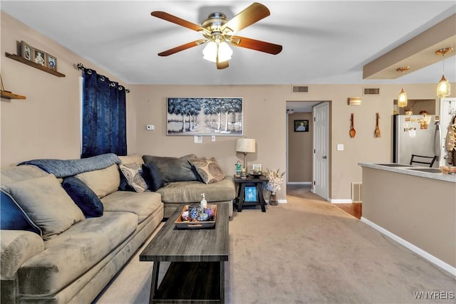 living room with carpet flooring, baseboards, visible vents, and ceiling fan