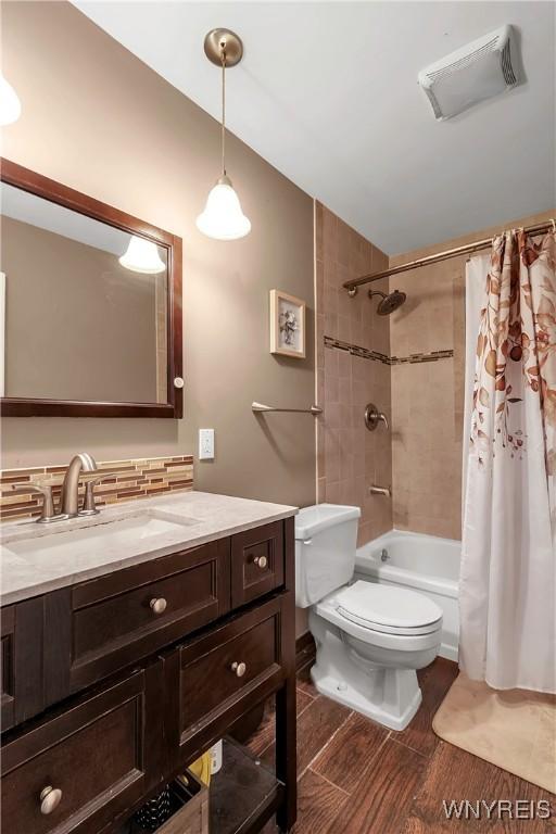 bathroom with vanity, wood finished floors, visible vents, shower / bath combination with curtain, and toilet