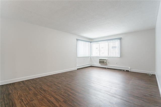 spare room featuring dark wood-type flooring, a wall unit AC, and a textured ceiling