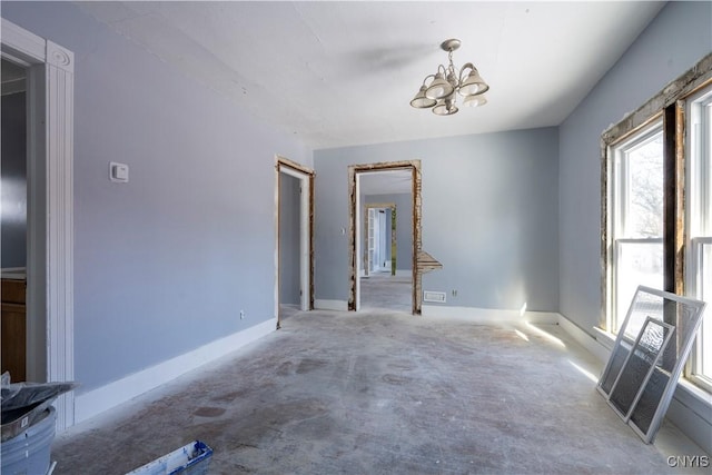 unfurnished room featuring a notable chandelier and concrete floors