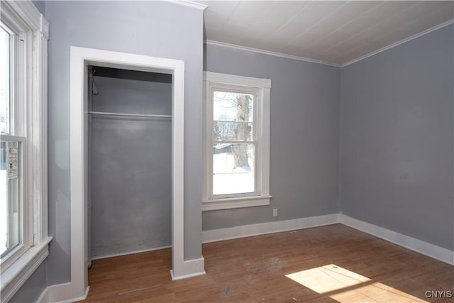 unfurnished bedroom featuring hardwood / wood-style floors, ornamental molding, and a closet