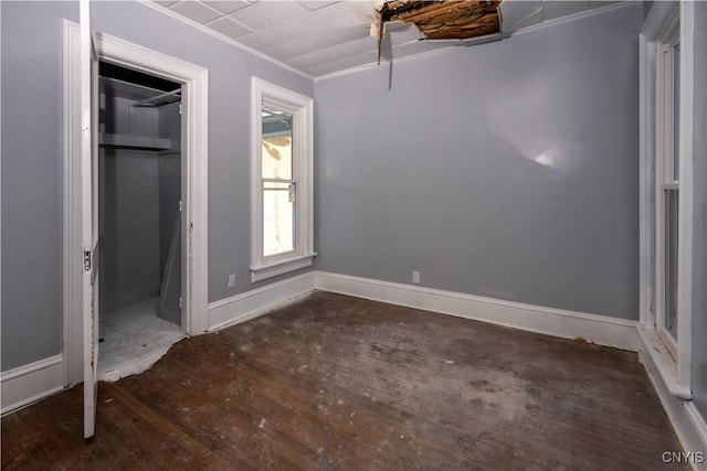 unfurnished bedroom featuring dark wood-type flooring, ornamental molding, and a closet