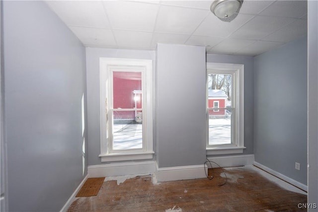 unfurnished room with hardwood / wood-style flooring and a drop ceiling