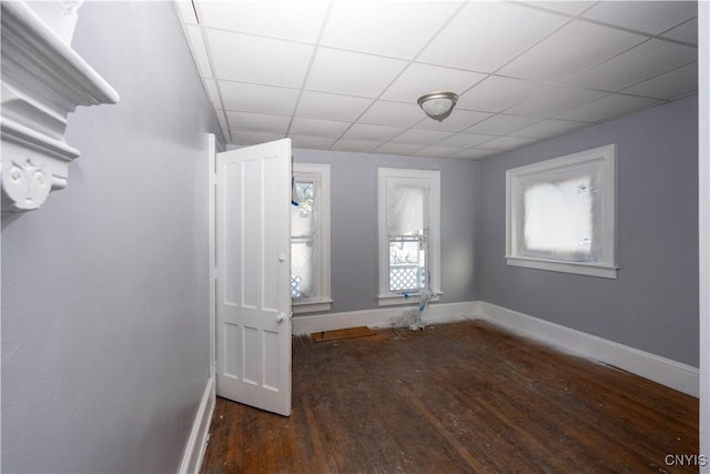 empty room with dark wood-type flooring and a drop ceiling