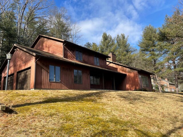 rear view of house featuring a garage and a yard