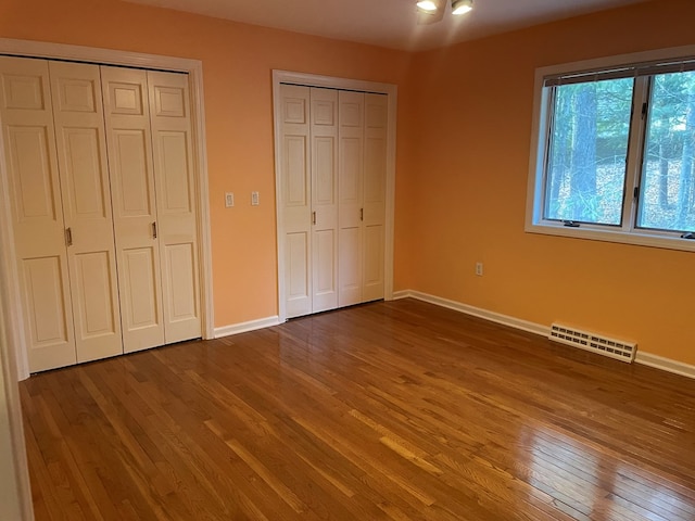 unfurnished bedroom featuring multiple closets and hardwood / wood-style flooring