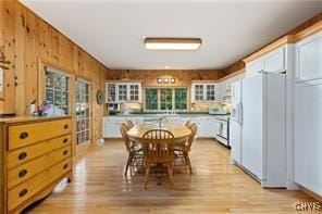 dining room featuring light wood-type flooring and wood walls