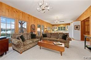 carpeted living room with wooden walls and a chandelier