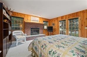 bedroom featuring access to exterior, a fireplace, and wood walls