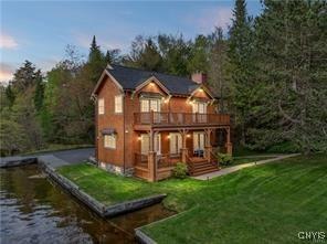 back house at dusk featuring a water view and a yard