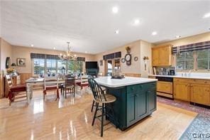 kitchen with a breakfast bar, dishwasher, hanging light fixtures, a center island, and a notable chandelier