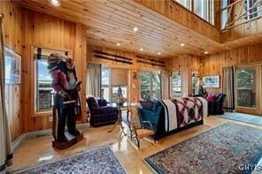 bedroom with a towering ceiling, wooden ceiling, light hardwood / wood-style floors, and wood walls