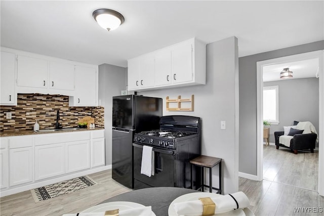 kitchen with white cabinetry, sink, tasteful backsplash, and black appliances