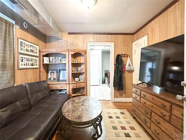 living area featuring visible vents, wood walls, and ornamental molding