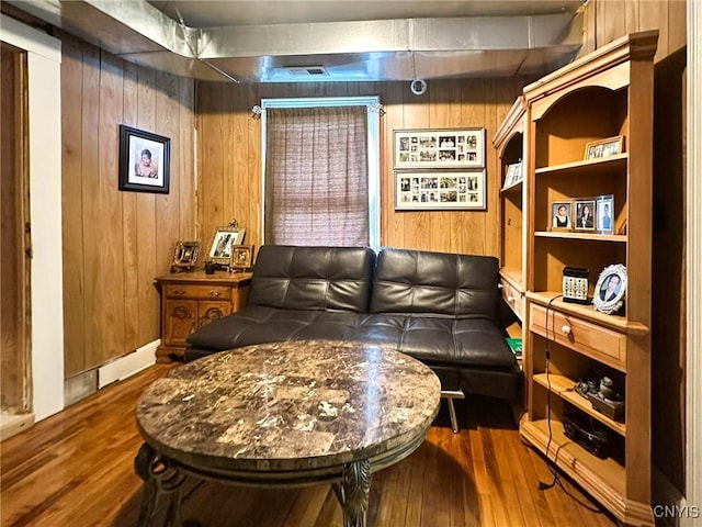 living area with wooden walls, wood finished floors, and visible vents