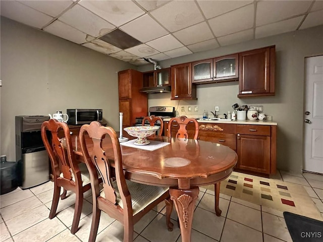 dining space with light tile patterned flooring and a paneled ceiling