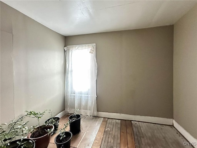 unfurnished room with baseboards and hardwood / wood-style flooring