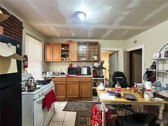 kitchen with open shelves, stainless steel microwave, brown cabinetry, light tile patterned floors, and white range with gas stovetop