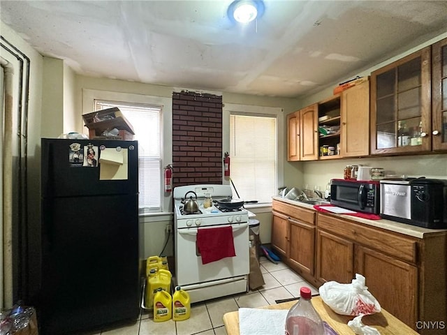 kitchen featuring brown cabinets, open shelves, white gas range oven, freestanding refrigerator, and light tile patterned floors