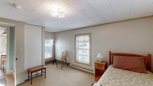 bedroom featuring light colored carpet, ornamental molding, and a baseboard heating unit