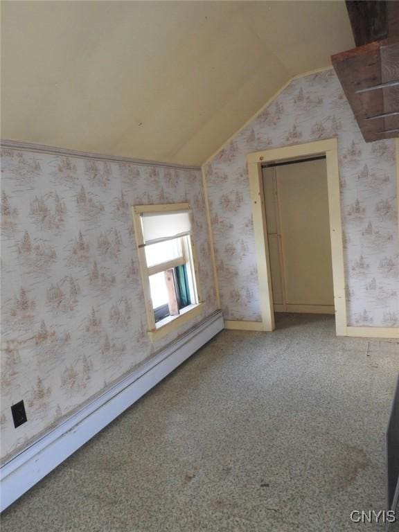 unfurnished room with a baseboard heating unit, vaulted ceiling, and carpet