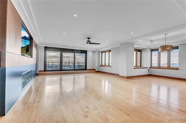 unfurnished living room featuring a fireplace, ornamental molding, ceiling fan, and light wood-type flooring