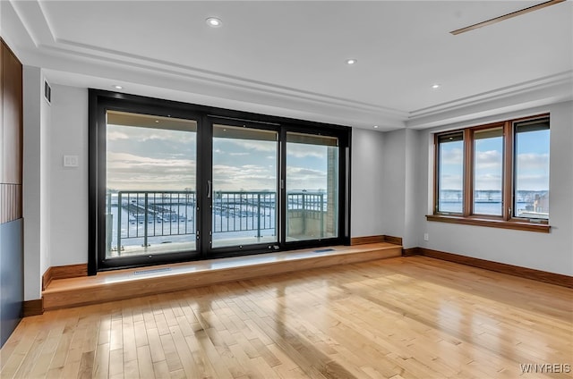 unfurnished room with a raised ceiling and light hardwood / wood-style flooring