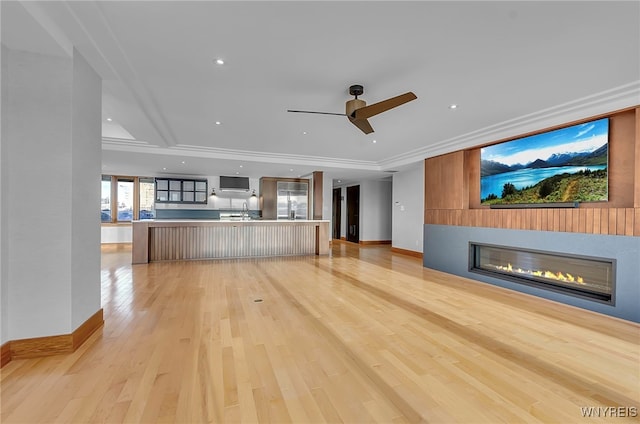 unfurnished living room featuring sink, ornamental molding, ceiling fan, and light wood-type flooring