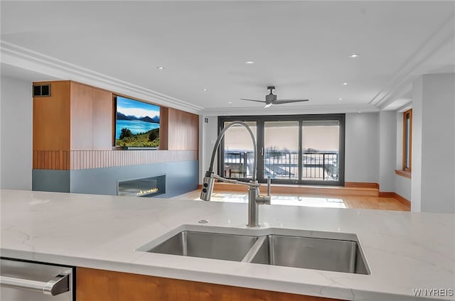 kitchen with light stone counters, sink, ornamental molding, and dishwasher