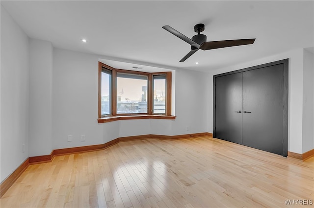 unfurnished bedroom with ceiling fan, light wood-type flooring, and a closet