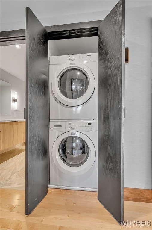 laundry room with stacked washer / dryer and hardwood / wood-style flooring