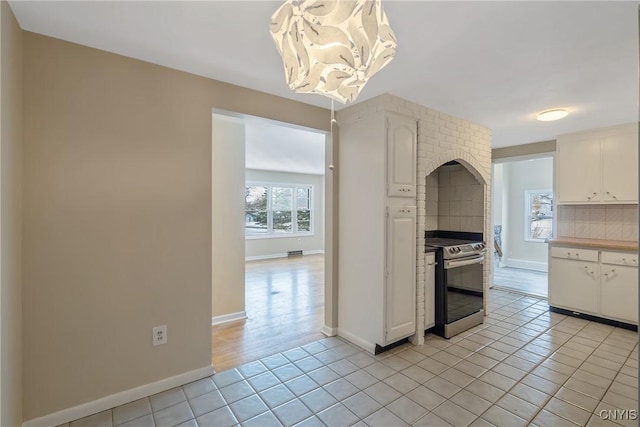 kitchen featuring tasteful backsplash, light tile patterned floors, white cabinets, and stainless steel electric range oven