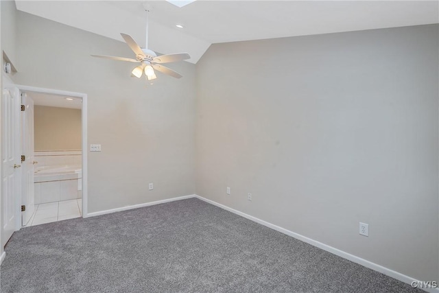 carpeted spare room featuring lofted ceiling with skylight and ceiling fan