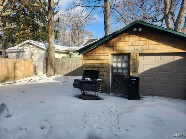 snow covered garage featuring fence