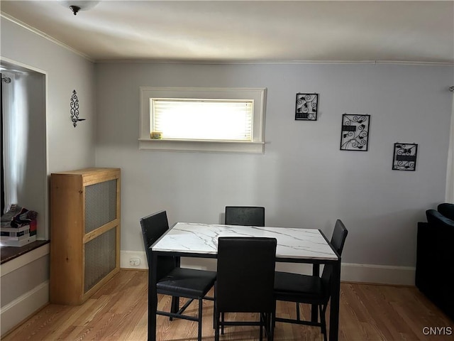 dining space with baseboards, wood finished floors, and ornamental molding