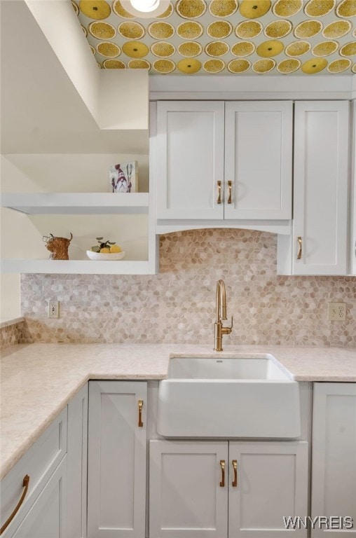 kitchen with tasteful backsplash, white cabinetry, and sink